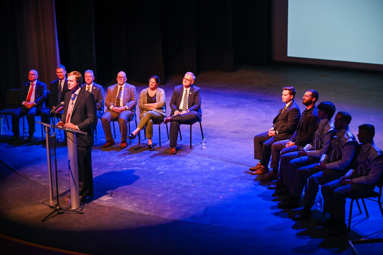 Senior Patron Duncan Sandys, former Lord Mayor of the City of Westminster talks Wednesday, March 22, 2023 in the Hayes Concert Hall while presenting the Marching Mocs with their official invitation to participate in the London New Year’s Day Parade.