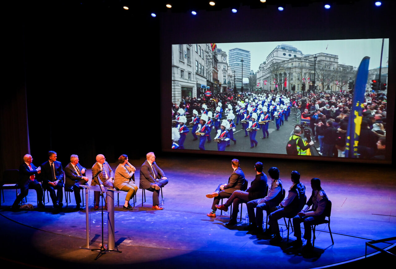 Representatives from the London Parade office and the city of London along with UTC representatives, watch footage of the London Parade Wednesday, March 22, 2023 in the Hayes Concert Hall before presenting the Marching Mocs with their official invitation to participate in the London New Year’s Day Parade.