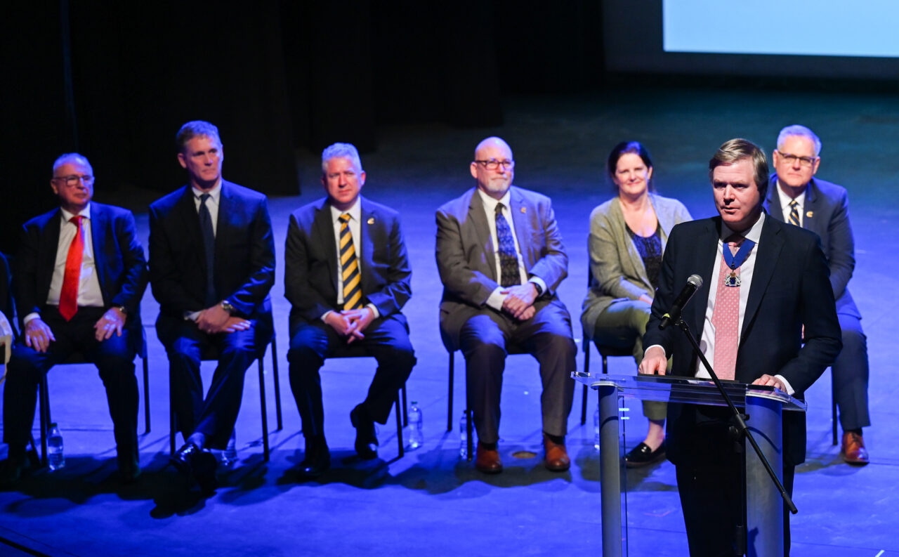 Senior Patron Duncan Sandys, former Lord Mayor of the City of Westminster talks Wednesday, March 22, 2023 in the Hayes Concert Hall while presenting the Marching Mocs with their official invitation to participate in the London New Year’s Day Parade.
