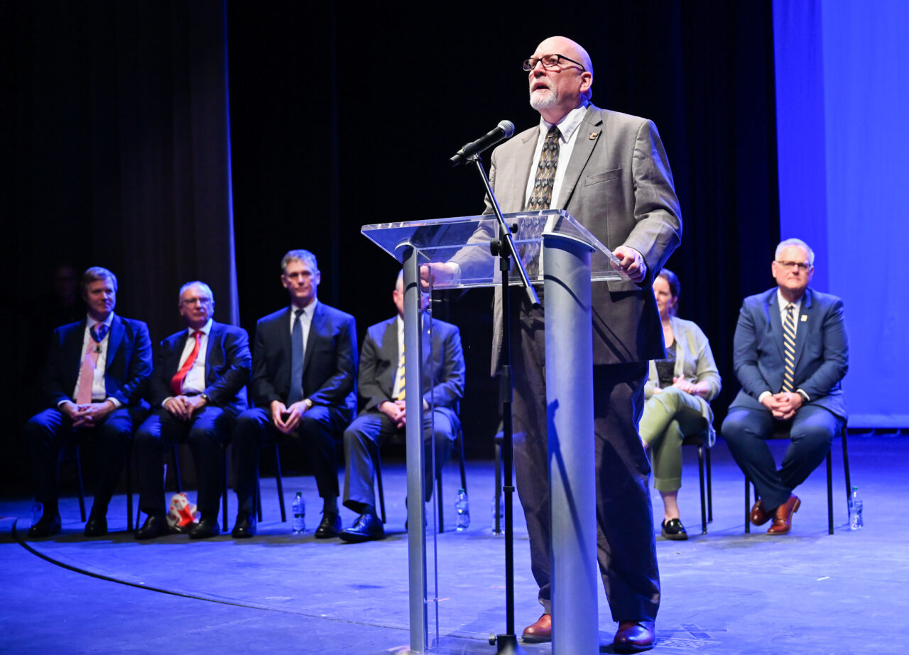 Jerold Hale speaks Wednesday, March 22, 2023 in the Hayes Concert Hall during a ceremony in which representatives from the London Parade office and the city of London present the Marching Mocs with their official invitation to participate in the London New Year’s Day Parade.