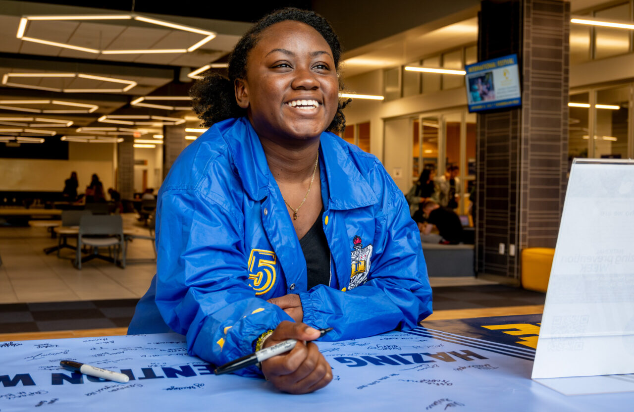 Chello Gardner signs a banner as part of UTC Hazing Prevention Week 2023's Campus Outreach Day. As part of National Hazing Prevention Week, the Office of Multicultural Affairs had a tabling event in the Lupton Hall lobby (photo by Mason Edwards). 
