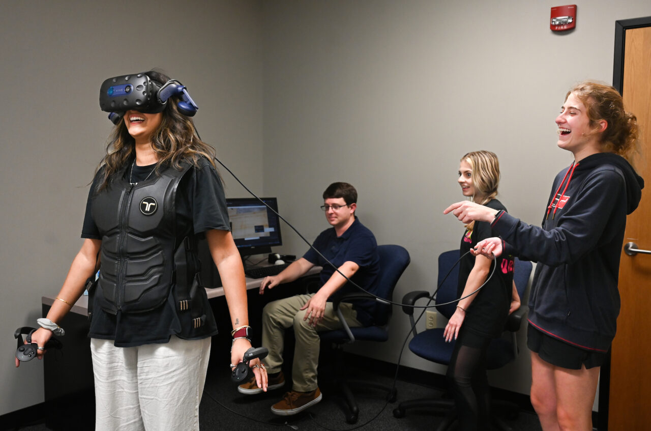 Graduate student Shyla Khan, left, uses virtual reality equipment under the watchful eye of Dr. Max Teaford and undergraduates Brianna Welch and Madison Murray. Photo by Angela Foster.