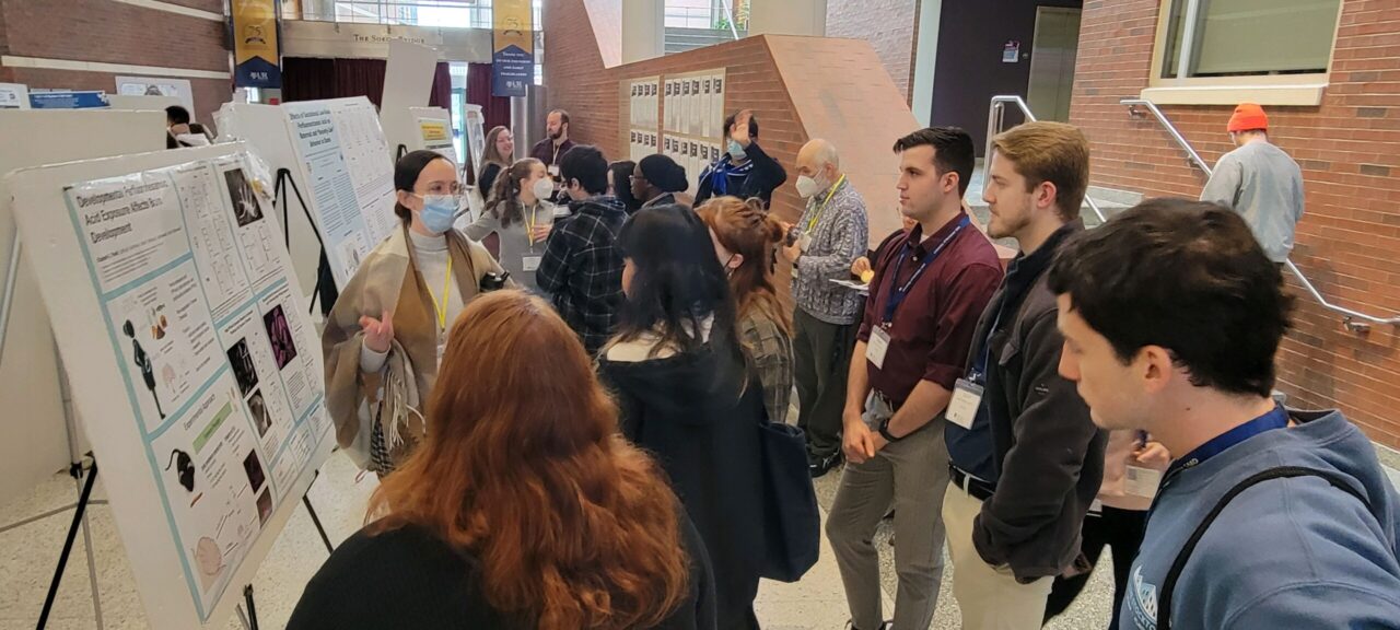 Elizabeth Plunk, in glasses and face mask, explains her poster presentation during the University of Rochester (New York) Medical Center Interview Weekend in February 2023. 