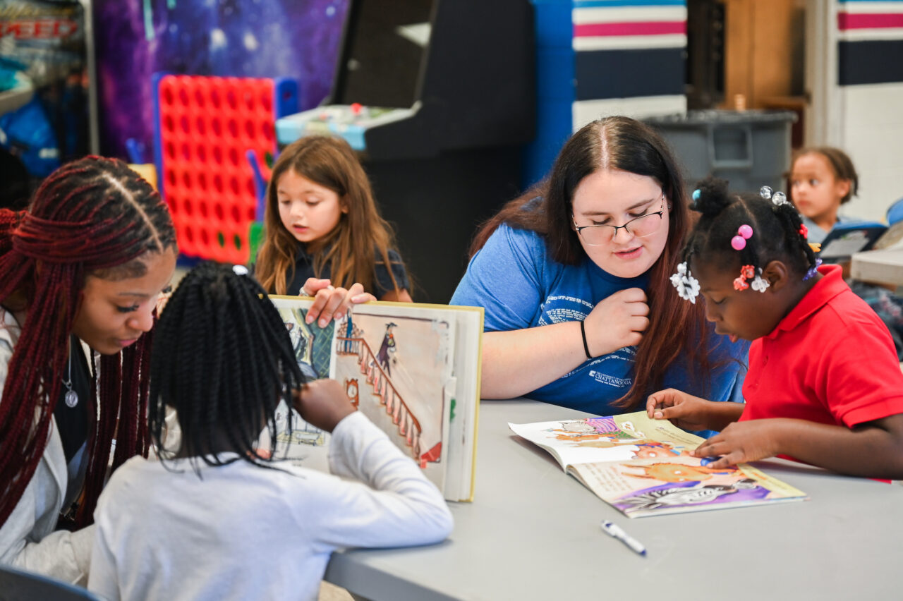 Anyssa Holloway (braids) and Lilly Tyler (blue shirt) read with students at the East Lake Salvation Army as part of Lori Waite’s Sociology of Social Problems class. Photo by Angela Foster.