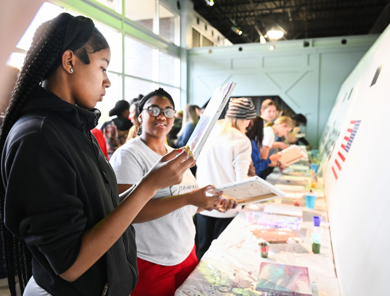 Criminal Justice students work with University High students Friday, Nov. 10, 2023 at the Challenger Center to pour paint on canvases.