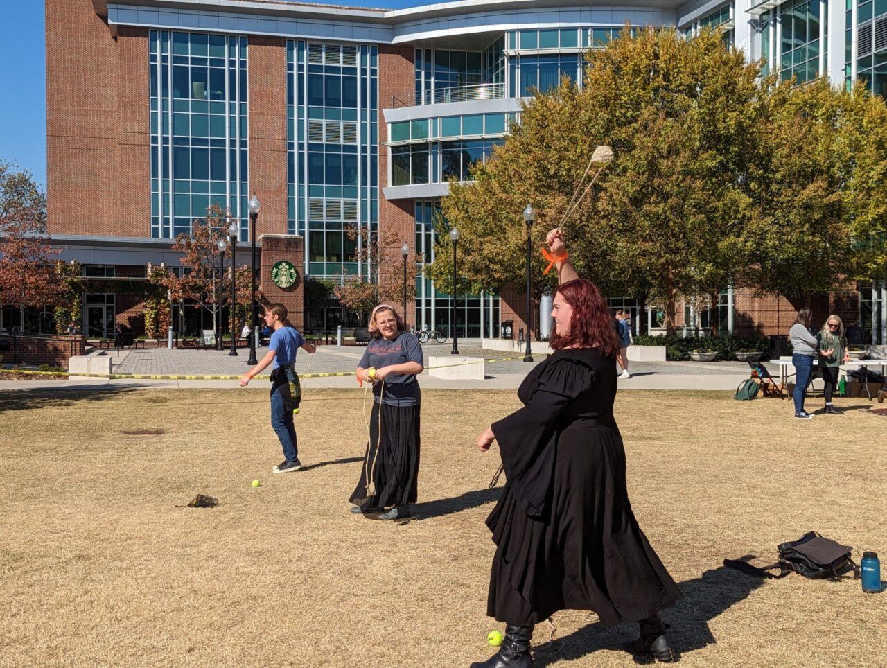 Students line up to practice using a woven sling to fling a woven ball, aiming for cardboard cutouts as targets. Traditional weaponry existed throughout global prehistory, across continents and a range of cultures. Photo credit: Dr. Andy Workinger.