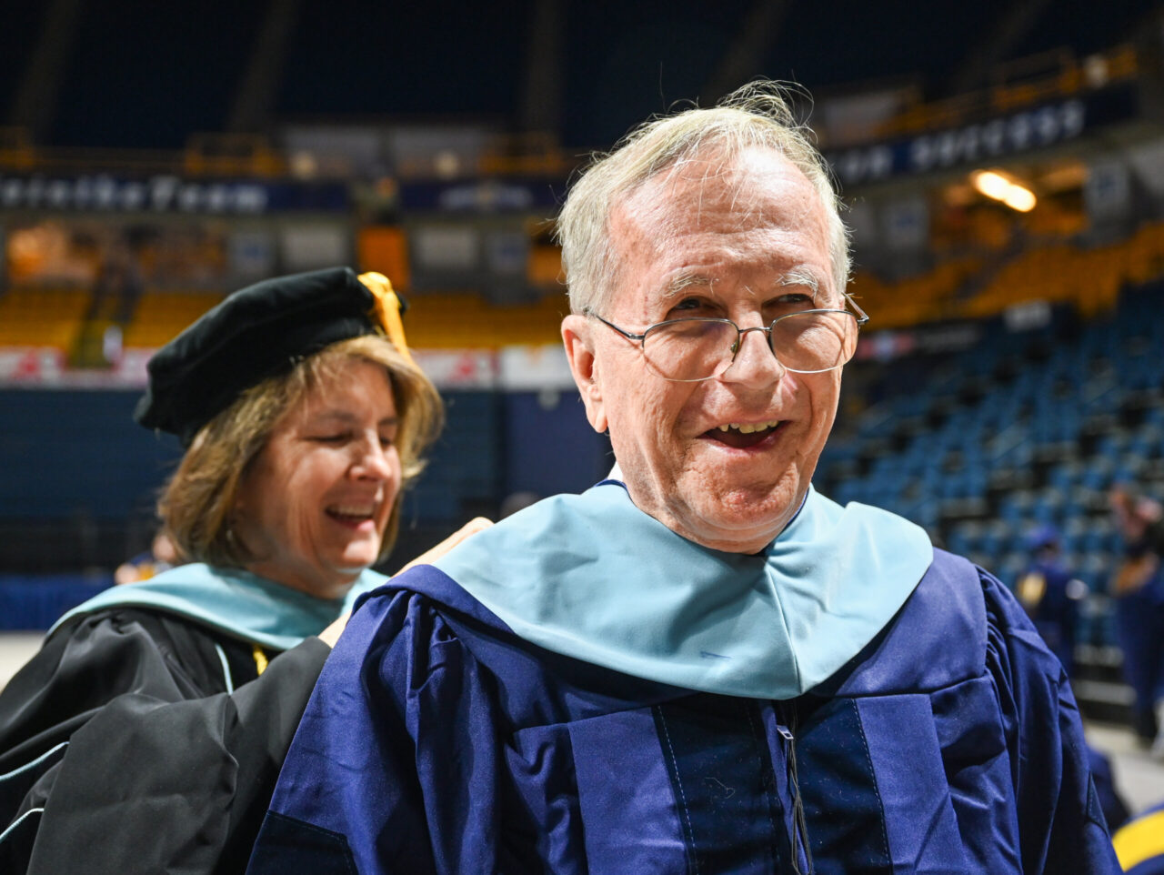 UC Foundation professor Beth Crawford adjusts Tony Galloway’s hood for photos before the Graduate School commencement Friday, Dec. 15, 2023 in McKenzie Arena at the University of Tennessee at Chattanooga.