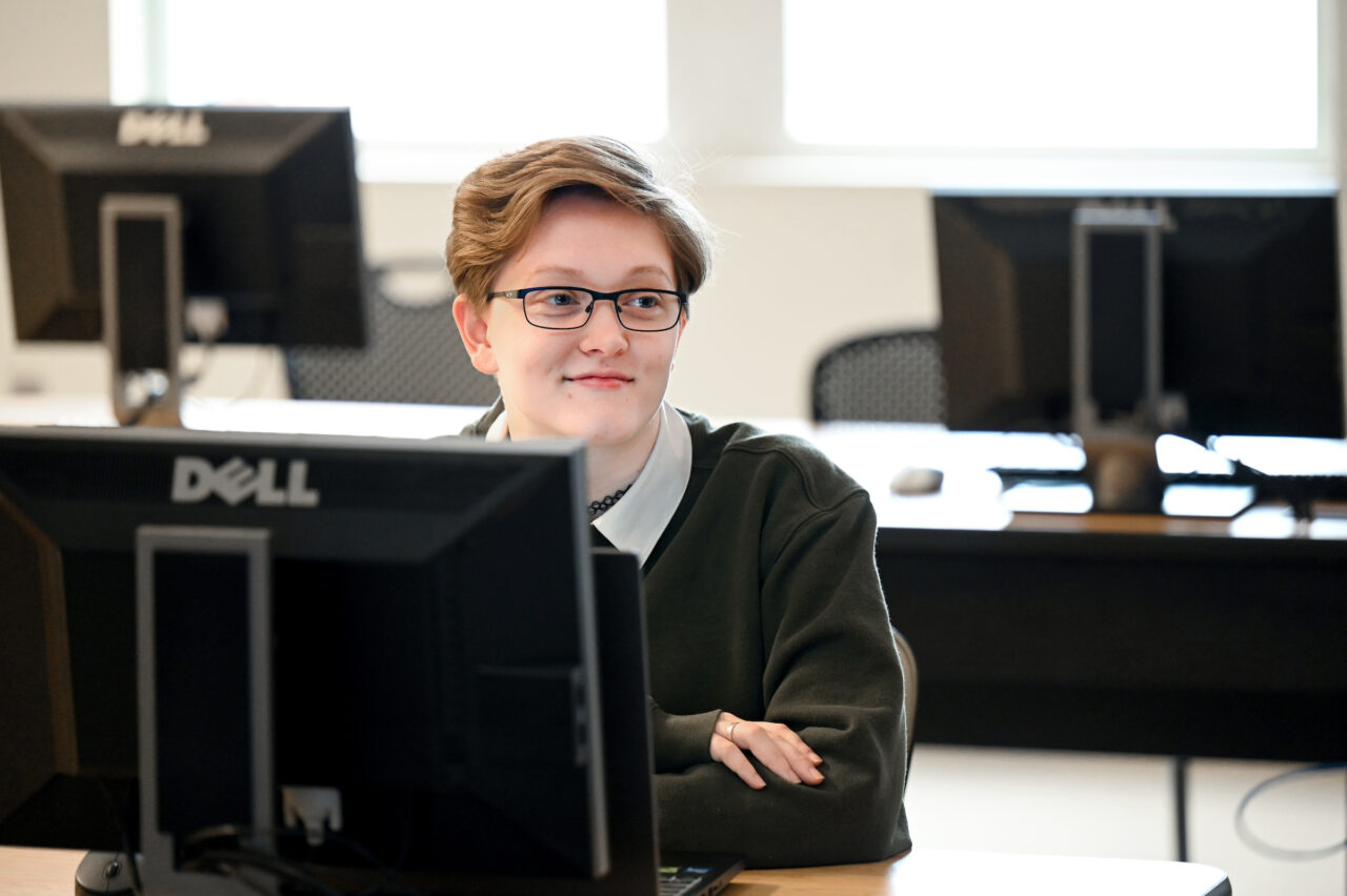 Katie Luck sits behind a computer keyboard in Assistant Professor of Practice Bill Worden’s Secure Mobile App Development class in the Engineering and Computer Science building. Photo by Angela Foster.