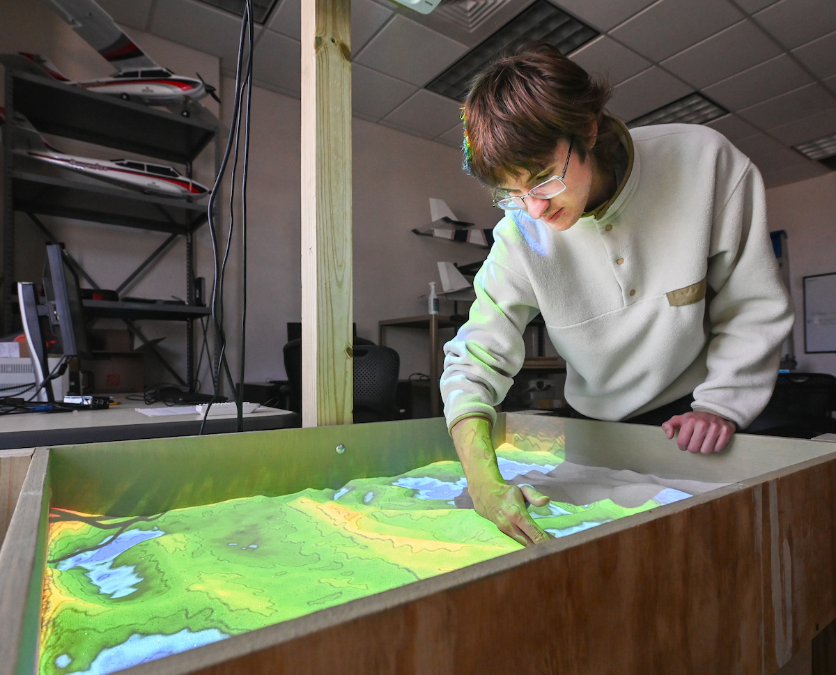 Electrical engineering major Nicholas Margavio demonstrates the augmented reality sandbox. Margavio was part of the UTC team that built the AR sandbox for Westview Elementary School.