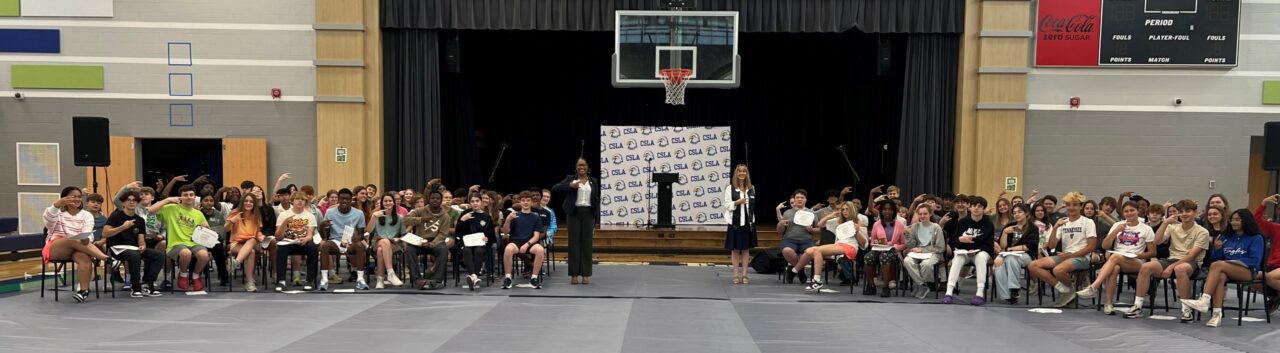 Stacy Lightfoot and Amy Hitchcock display the “Power C” to Chattanooga School for the Liberal Arts-promoted eighth graders after sharing the news about the Middle School to Mocs Scholars program.