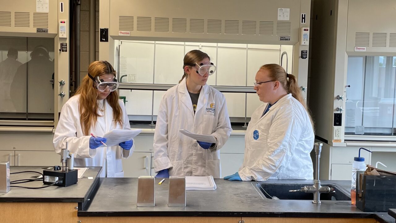 Polymer chemistry students Maya Sharma, left, and Morgan Williams discuss their experimental design with Kaitlyn Cathers, a development technician at Woodbridge Foam Corporation. Photo credit: Dr. Meredith Barbee.