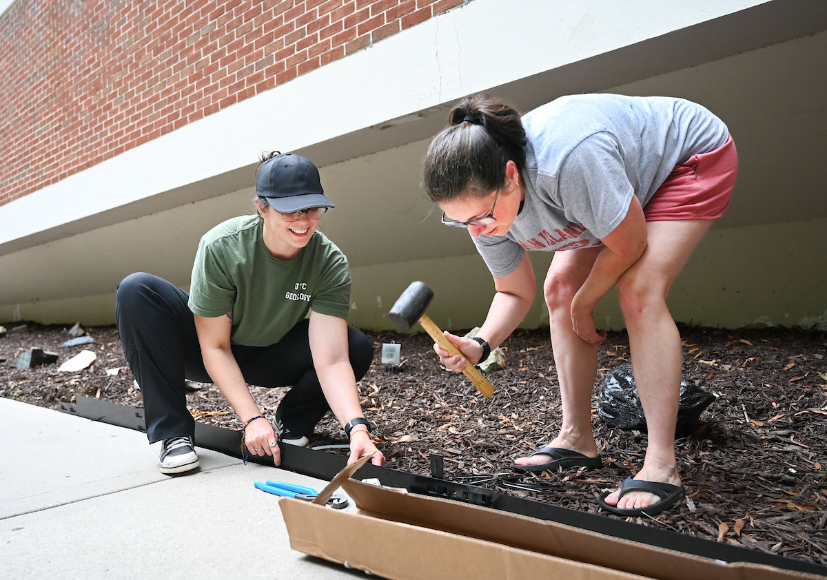 Senior environmental geology major Samantha Doss-Watson, left, and Dr. Amy Brock-Hon install edging around The Rockery—a rock garden located outside of Grote Hall—on Tuesday, June 4. Photo by Angela Foster.