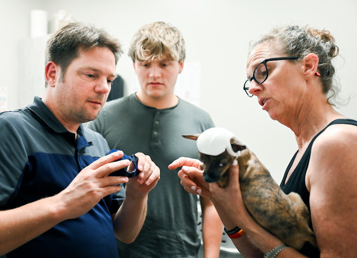 Trevor Elliott and Connor Mackey work Monday, July 15, 2024 to try out 3-D printed helmets for a puppy at the Humane Educational Society.