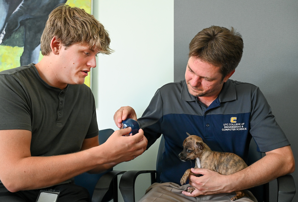 Trevor Elliott and Connor Mackey work Monday, July 15, 2024 to try out 3-D printed helmets for a puppy at the Humane Educational Society.