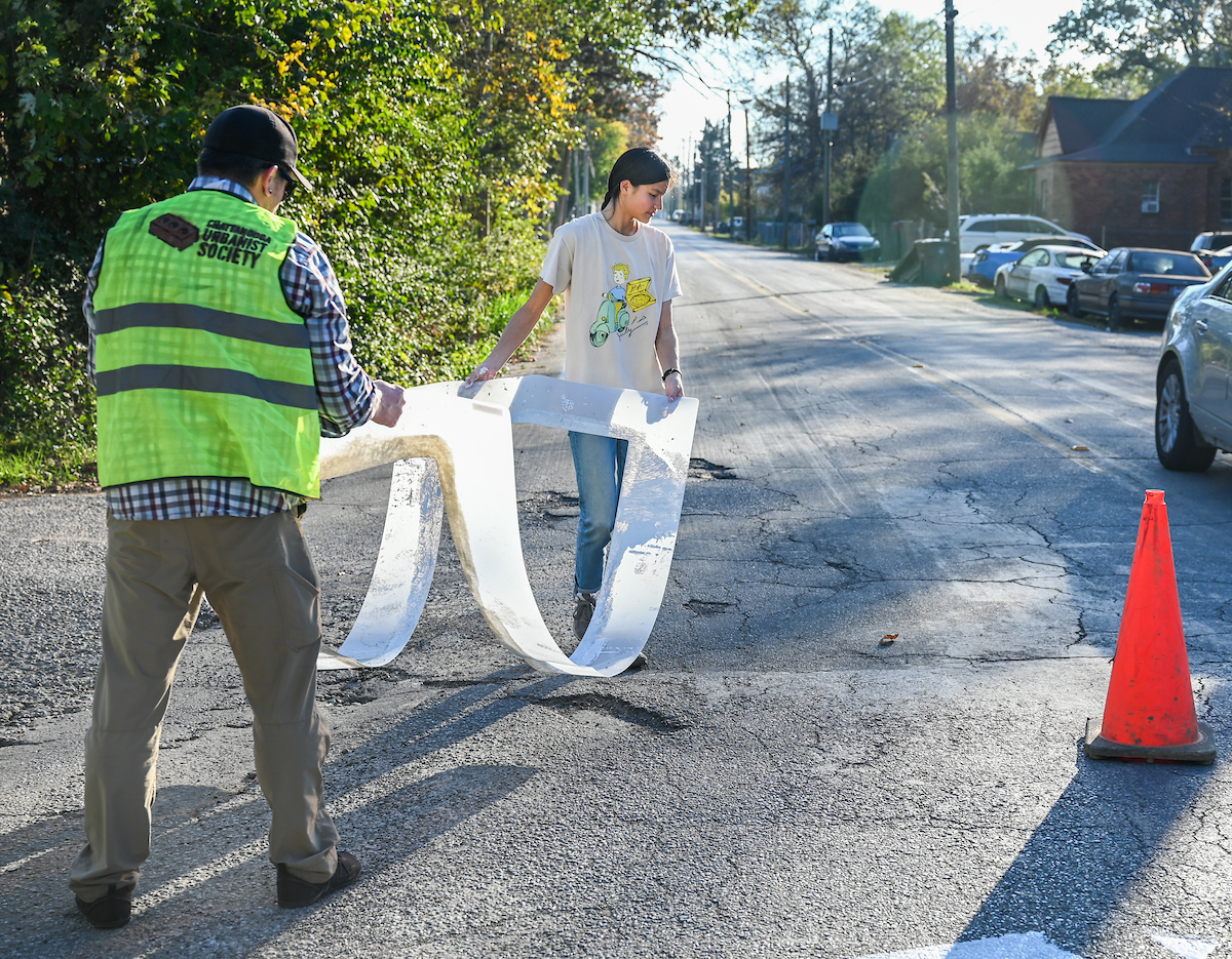 Students in Chandra Ward’s Innovation in Honors class work Monday, Nov. 18, 2024 to put up tactical urbanism traffic calming installations in the Oak Grove neighborhood.