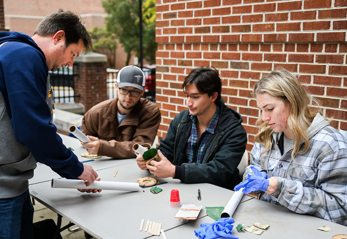 Rocket Mocs Faculty Advisor Trevor Elliott, left, consults with Eli Welch, team lead Nathan Gastelum and Addi Whittemore during a Nov. 15 rocket build outside the College of Engineering and Computer Science. Photo by Angela Foster.