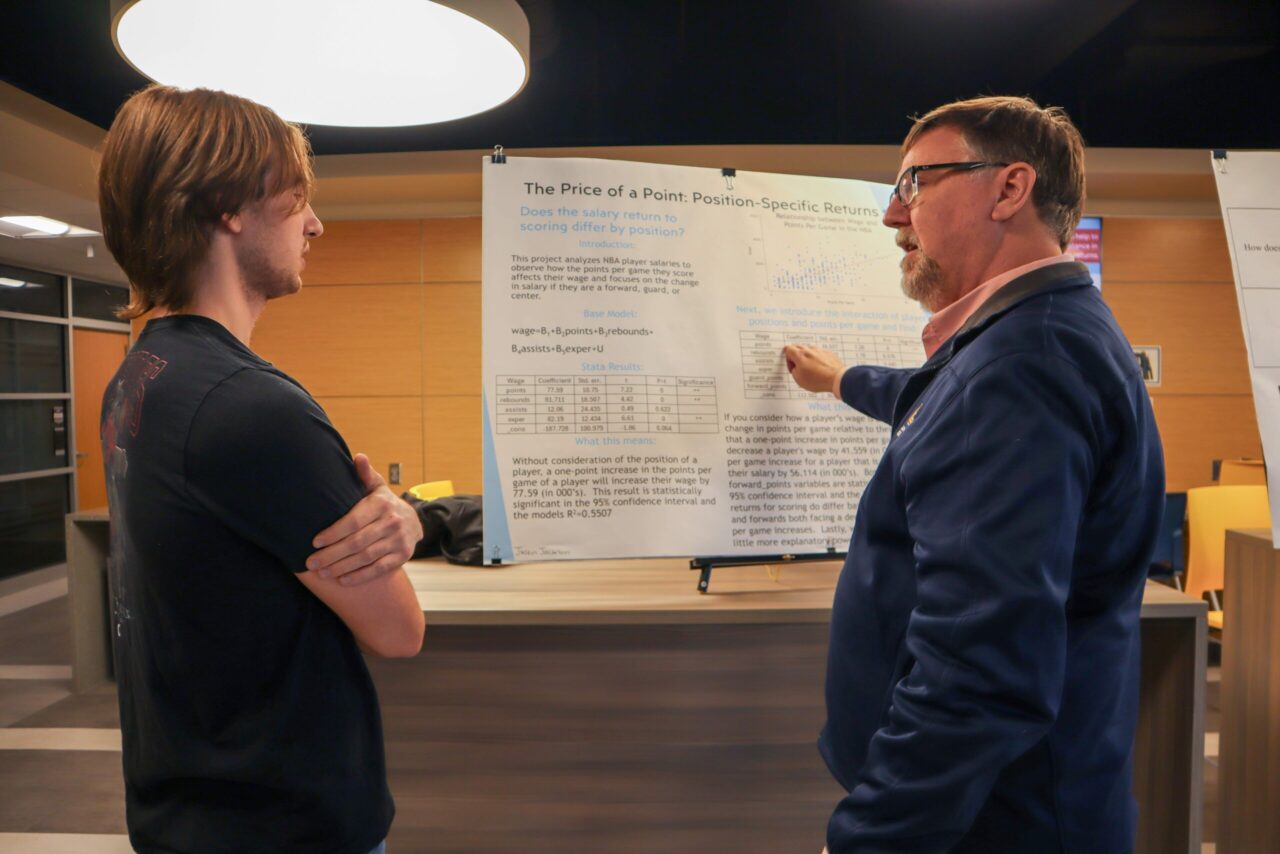 Justin Jackson, discusses his project with Center for Regional Economic Research Director Howard Wall at the Econometrics Research Symposium. Photo by Omar Yasin.