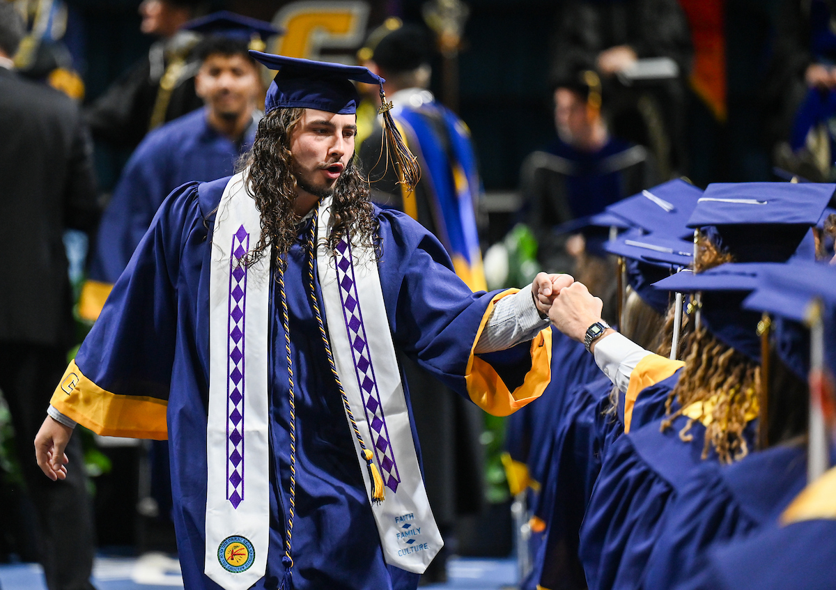 University of Tennessee at Chattanooga student Nathanael Jones greets a student on the way back to his seat Saturday, Dec. 14, 2024 during the undergraduate commencement ceremony in McKenzie Arena.