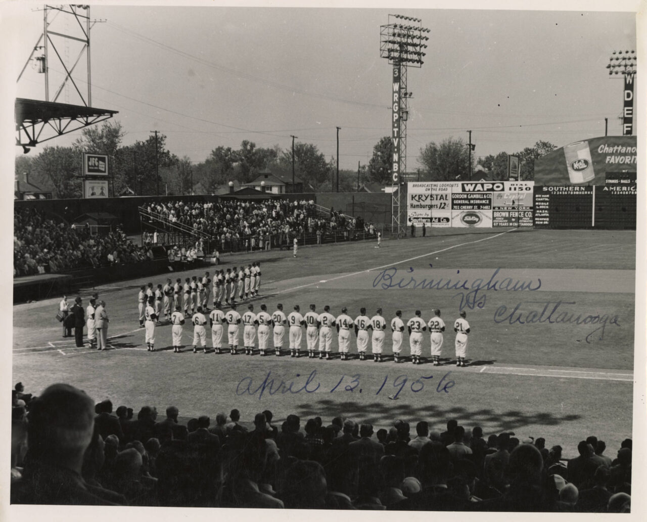 Black-and-white photograph of the Chattanooga Lookouts and the Birmingham Barons in Engel Stadium standing for the national anthem before a game on April 13, 1956.