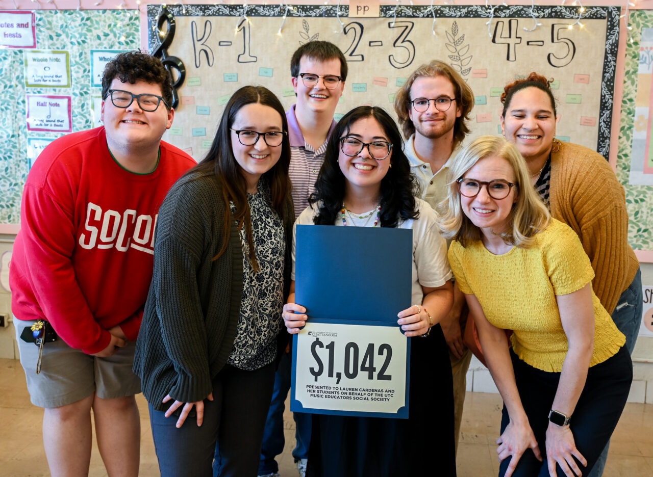 Music students Collin Sutton, Emily Bruce, Christian Cantrell, Bradley Bee and Remington Prado-Bonner and Associate Professor Ali Allerton (yellow top) surround DuPont Elementary School music teacher Lauren Cardenas after presenting her with a gift of $1,042 for school supplies. Photo by Angela Foster.