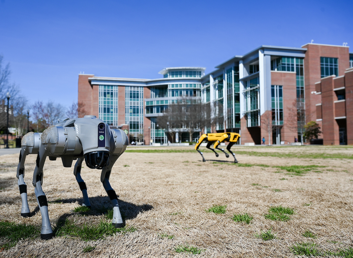 Gokhan Erdemir, Ann McAbee and Trevor Kight work Friday, Feb. 28, 2025 on Chamberlain Field to gather data from two robotic dogs, Spot and Goddard. The data will be compared against data from real dogs and used to make the robots move more like real dogs.