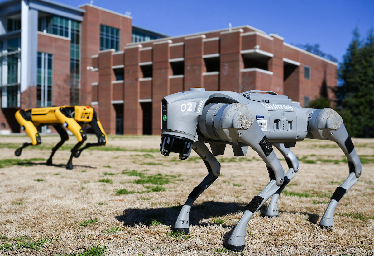 Gokhan Erdemir, Ann McAbee and Trevor Kight work Friday, Feb. 28, 2025 on Chamberlain Field to gather data from two robotic dogs, Spot and Goddard. The data will be compared against data from real dogs and used to make the robots move more like real dogs.