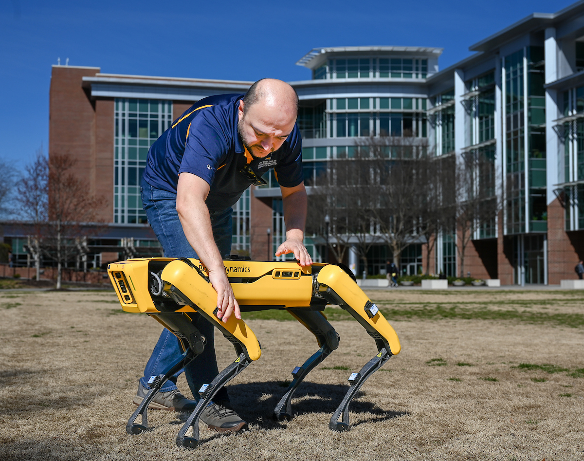 Gokhan Erdemir, Ann McAbee and Trevor Kight work Friday, Feb. 28, 2025 on Chamberlain Field to gather data from two robotic dogs, Spot and Goddard. The data will be compared against data from real dogs and used to make the robots move more like real dogs.