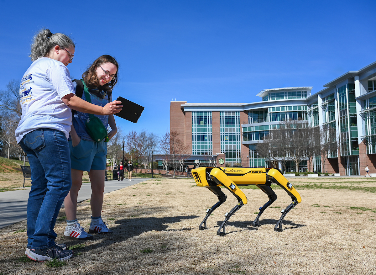 Gokhan Erdemir, Ann McAbee and Trevor Kight work Friday, Feb. 28, 2025 on Chamberlain Field to gather data from two robotic dogs, Spot and Goddard. The data will be compared against data from real dogs and used to make the robots move more like real dogs.