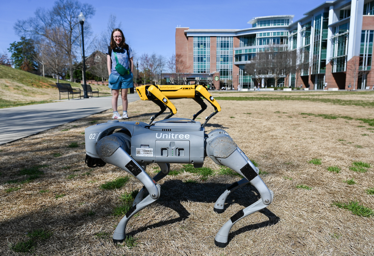 Gokhan Erdemir, Ann McAbee and Trevor Kight work Friday, Feb. 28, 2025 on Chamberlain Field to gather data from two robotic dogs, Spot and Goddard. The data will be compared against data from real dogs and used to make the robots move more like real dogs.