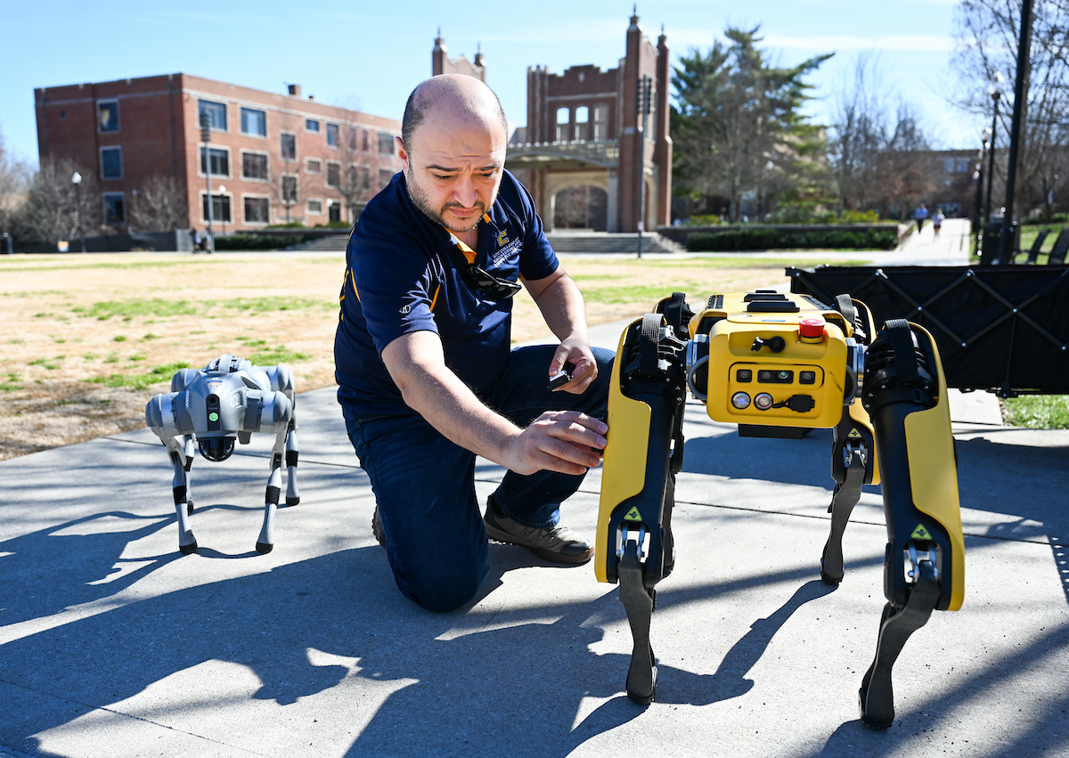 Gokhan Erdemir, Ann McAbee and Trevor Kight work Friday, Feb. 28, 2025 on Chamberlain Field to gather data from two robotic dogs, Spot and Goddard. The data will be compared against data from real dogs and used to make the robots move more like real dogs.