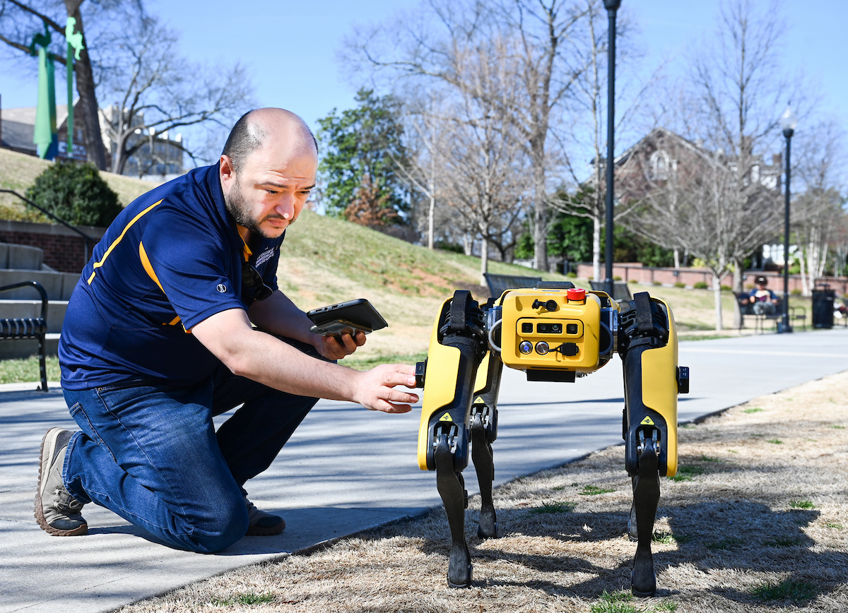Gokhan Erdemir, Ann McAbee and Trevor Kight work Friday, Feb. 28, 2025 on Chamberlain Field to gather data from two robotic dogs, Spot and Goddard. The data will be compared against data from real dogs and used to make the robots move more like real dogs.