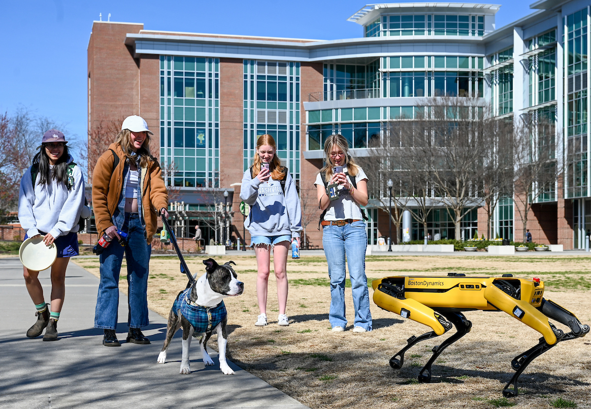 Gokhan Erdemir, Ann McAbee and Trevor Kight work Friday, Feb. 28, 2025 on Chamberlain Field to gather data from two robotic dogs, Spot and Goddard. The data will be compared against data from real dogs and used to make the robots move more like real dogs.