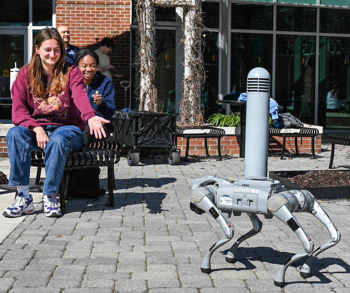 Gokhan Erdemir, Ann McAbee and Trevor Kight work Friday, Feb. 28, 2025 on Chamberlain Field to gather data from two robotic dogs, Spot and Goddard. The data will be compared against data from real dogs and used to make the robots move more like real dogs.