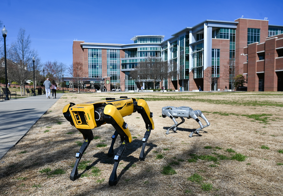 Gokhan Erdemir, Ann McAbee and Trevor Kight work Friday, Feb. 28, 2025 on Chamberlain Field to gather data from two robotic dogs, Spot and Goddard. The data will be compared against data from real dogs and used to make the robots move more like real dogs.