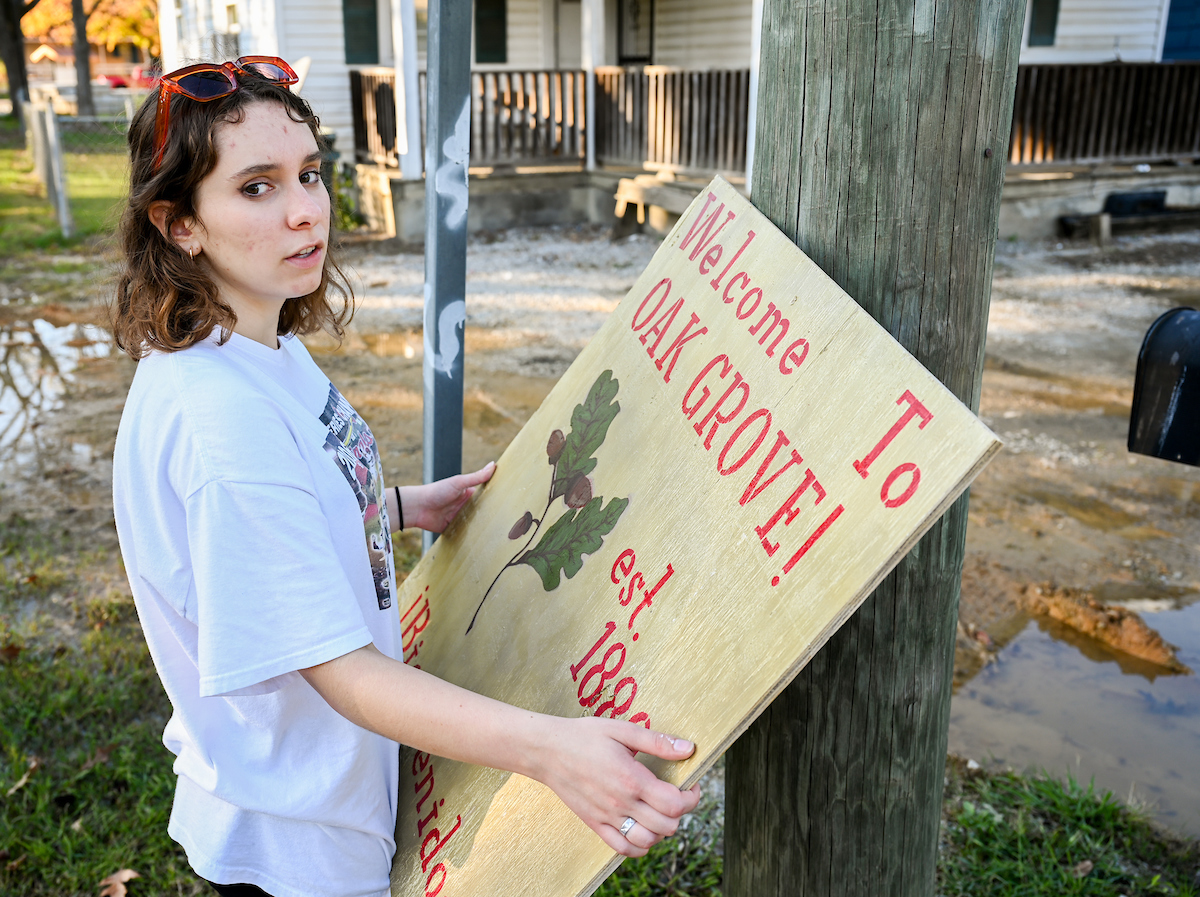 Caroline Schrader hangs a sign in the Oak Grove neighborhood. Photo by Angela Foster.