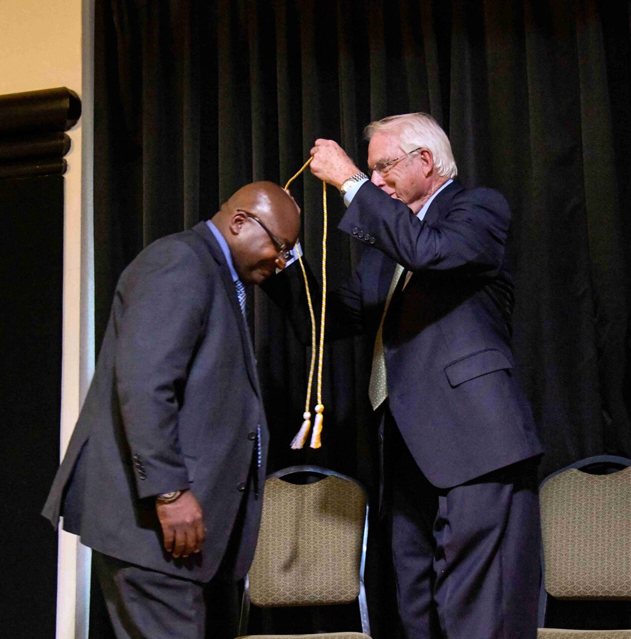 Calvin Woods, founder of Cal’s Headlight Restoration, left, receives his graduation cord from Urban Vision Initiative mentor Bill McDonald.