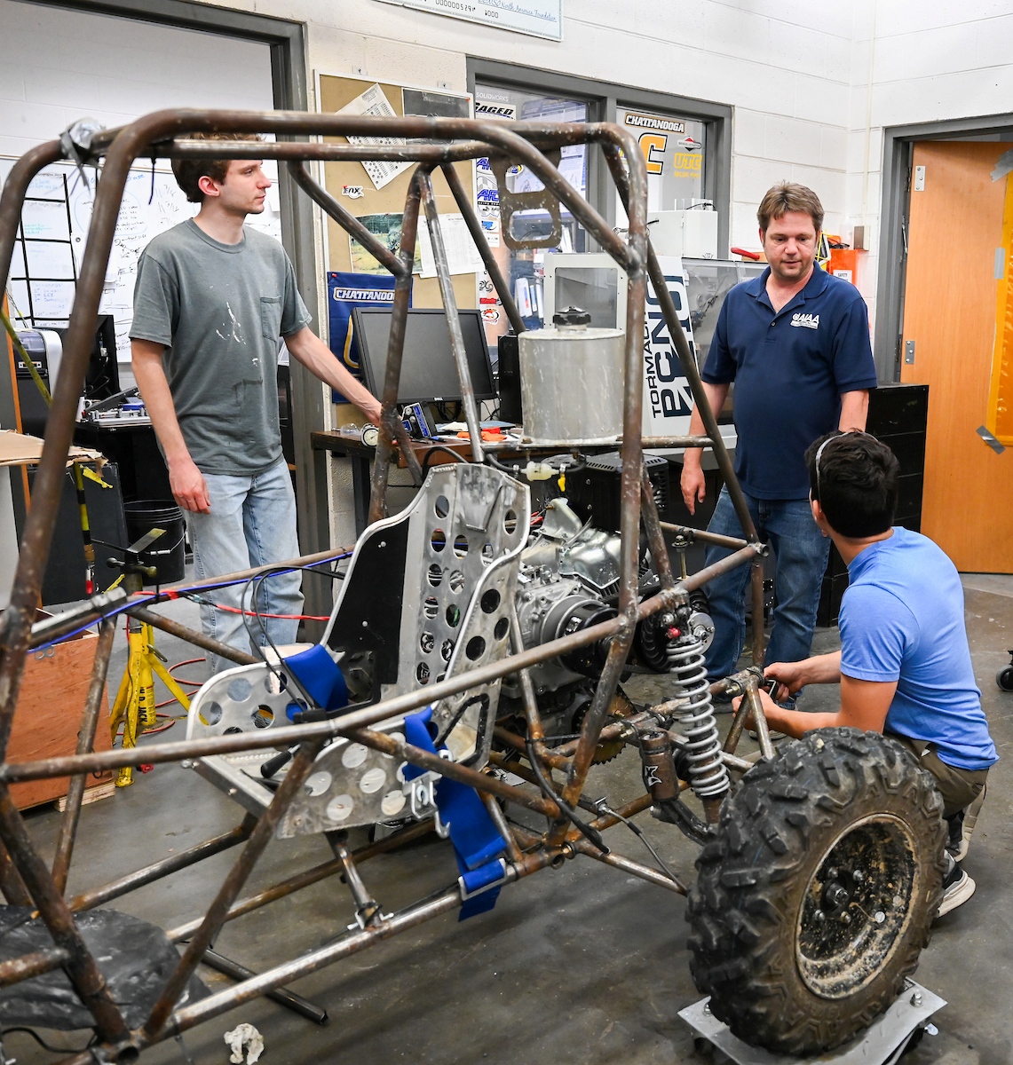 UC Foundation Associate Professor Trevor Elliott (solid blue shirt), who serves as the faculty advisor, discusses the ATV with members of the Baja team.