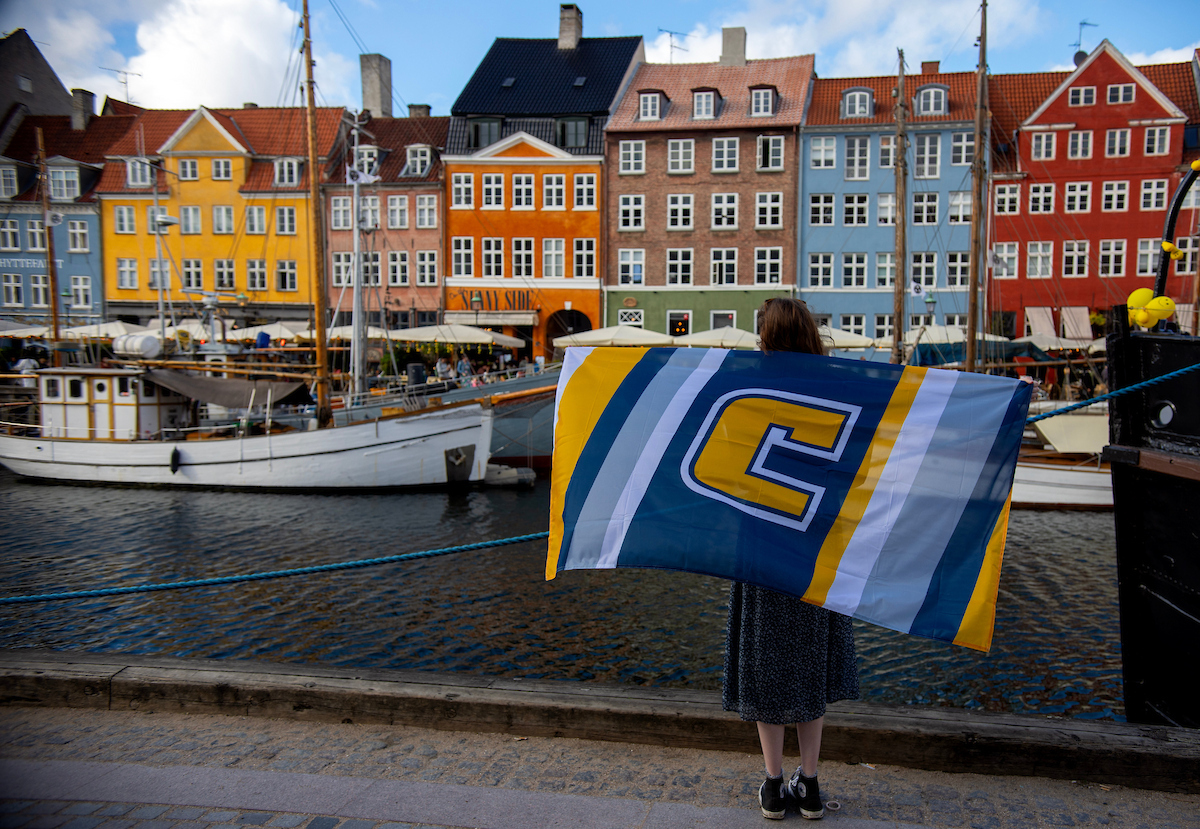 Sydney Banks holds the UTC flag in front of the Nyhavn Canal in Copenhagen. Photo by Clara Paulson.