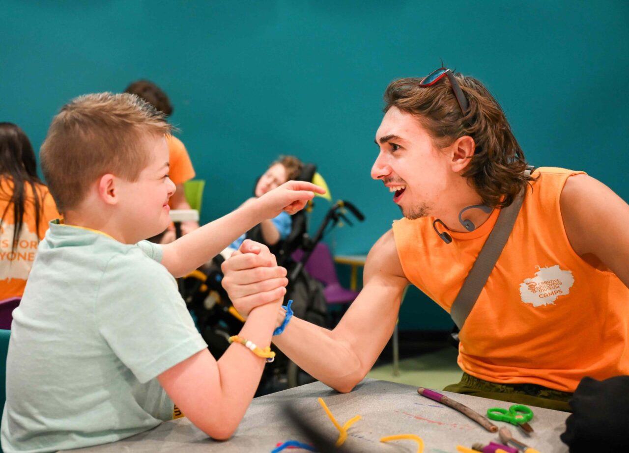 Brandon Gomes Toste arm wrestles Maverick during a session of the Creative Discovery Museum’s Friends’ Discovery Camps. Photo by Angela Foster.
