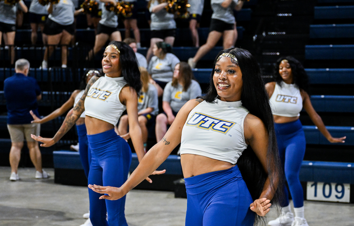 Several members of Ladies of Gold dancing with the crowd behind them