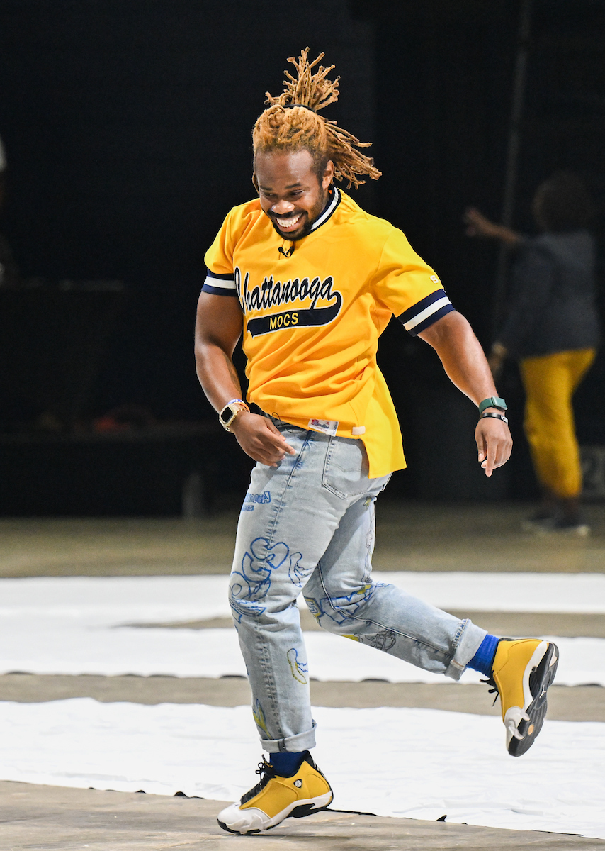 A man in a yellow UTC shirt dances on the McKenzie Arena floor.