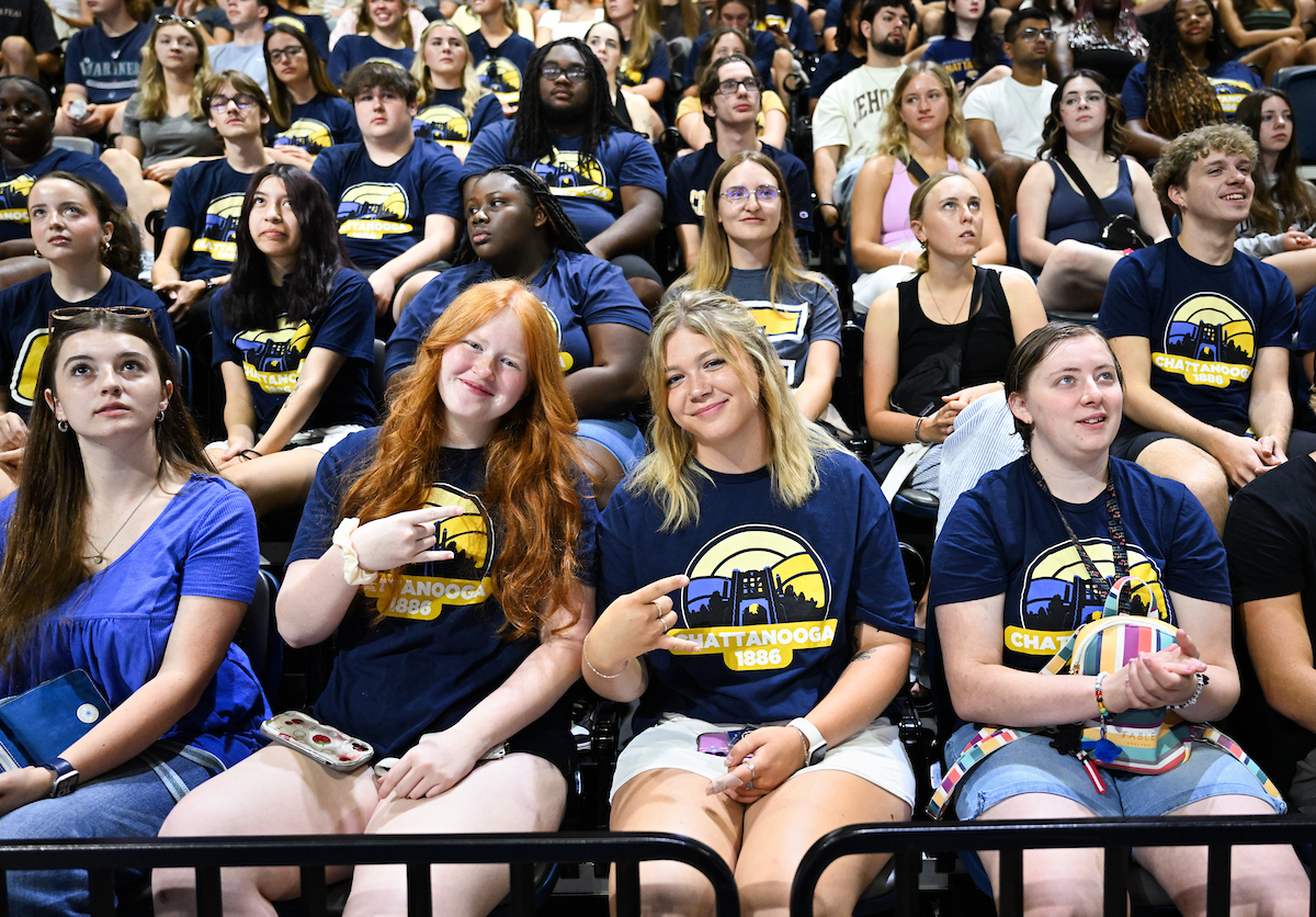 Students hold up a "Power C" sign in a crowd of other students at Convocation in McKenzie Arena