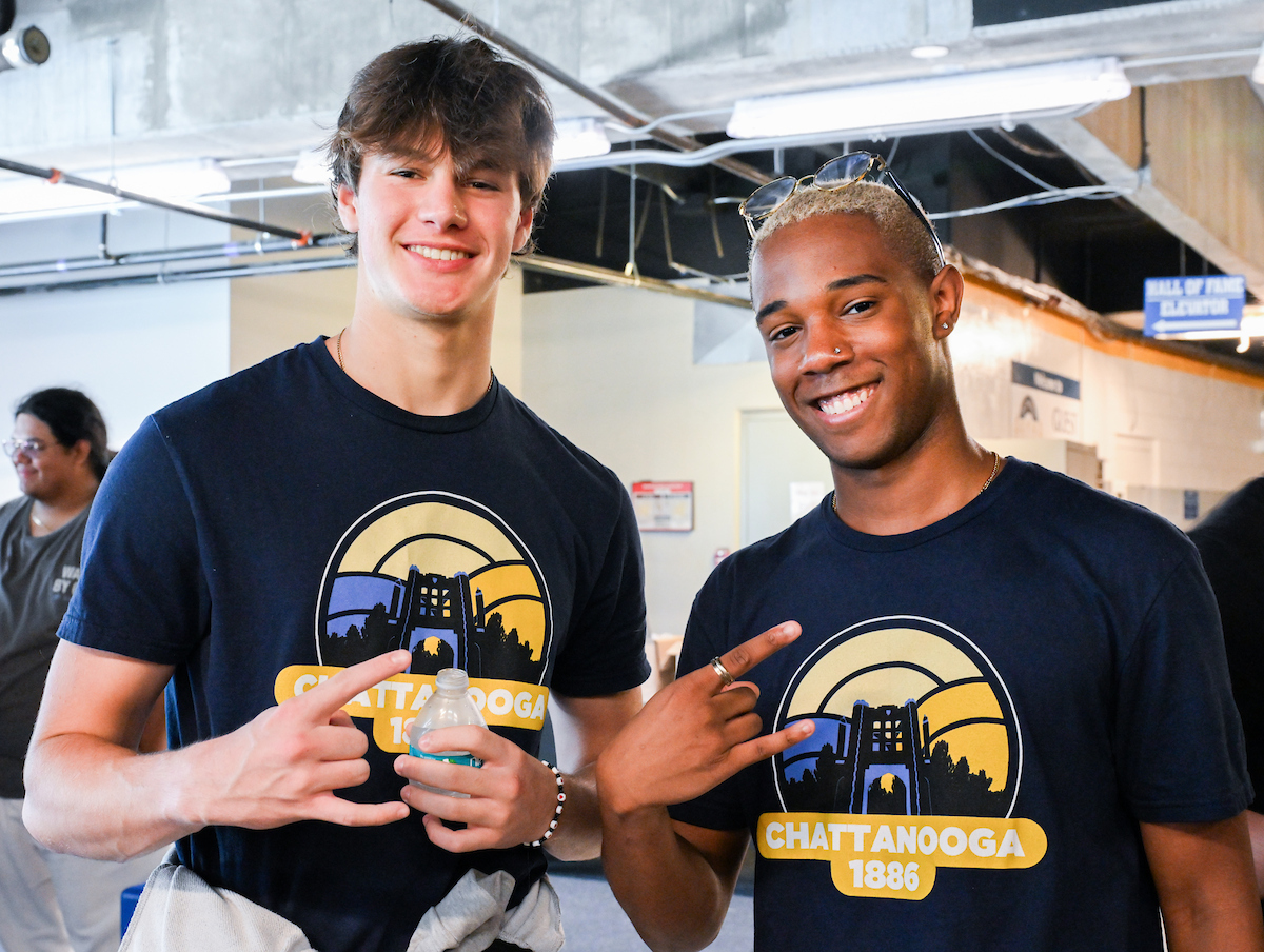 Two male students hold up a "Power C" symbol at the McKenzie Arena cookout.