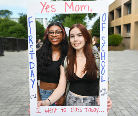 Two students standing inside a pretend photo frame reading "Yes, Mom, I went to class today. First day of School."