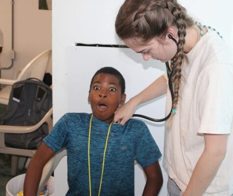 Gillian Morton uses a stethoscope to check vitals on a summer camp student