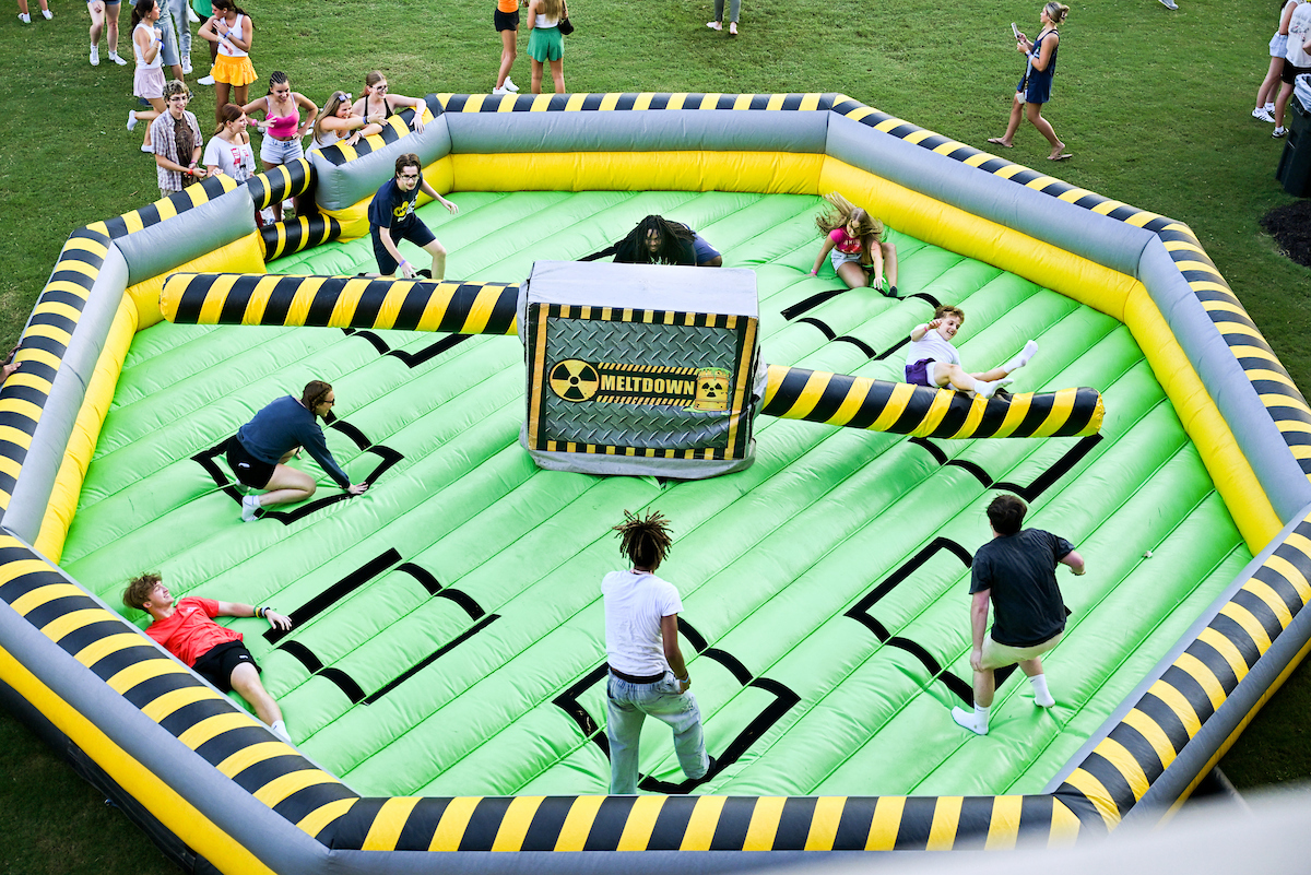 Students on an inflatable on Chamberlain Field, attempting to jump over an inflatable that knocks them over.