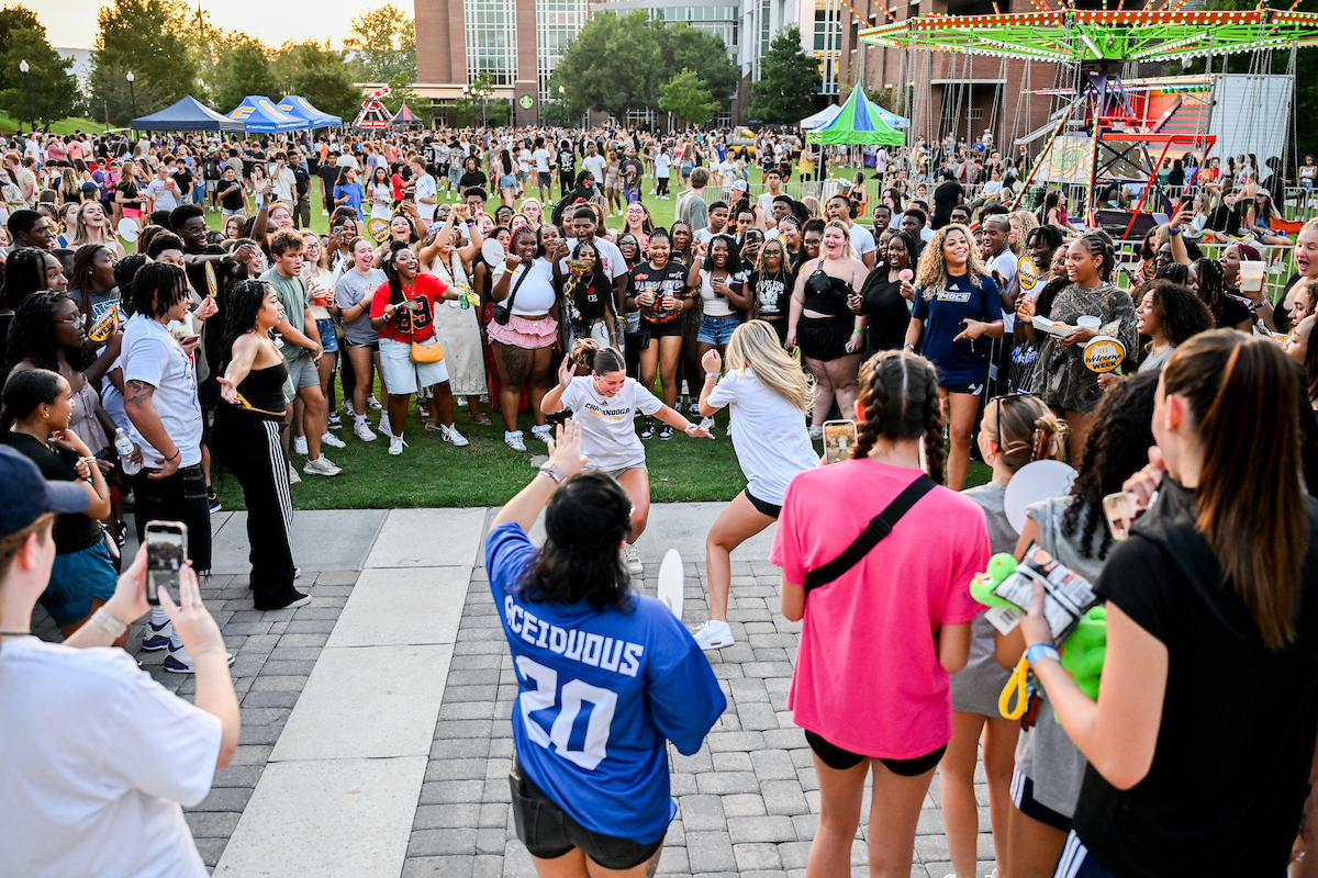 Students form a circle while two people dance in the middle during Welcome Week.