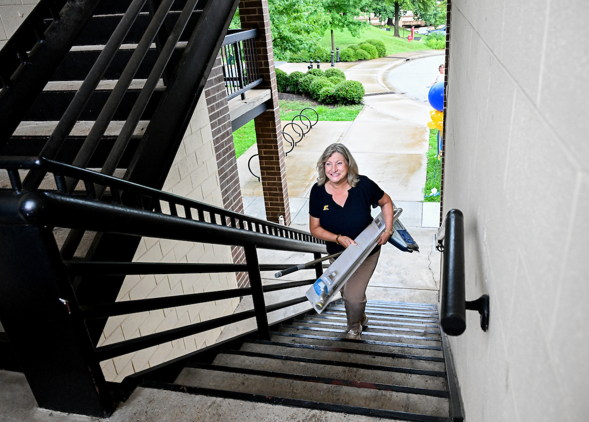 Chancellor Lori Bruce smiles as she carries a student's item up the stairs to help move her in.
