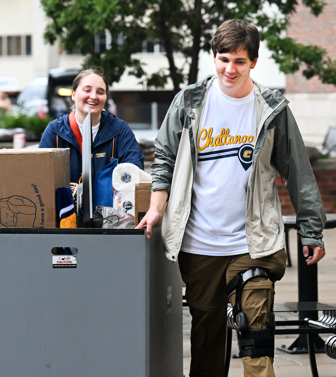Volunteers help roll in a students belongings into West Campus Housing.