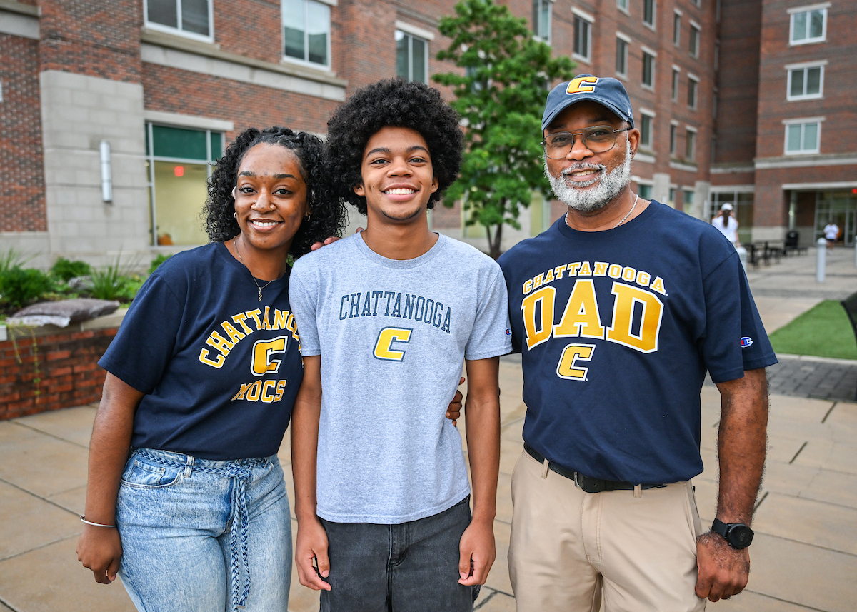 A family smiles as they stand outside of West Campus Housing.
